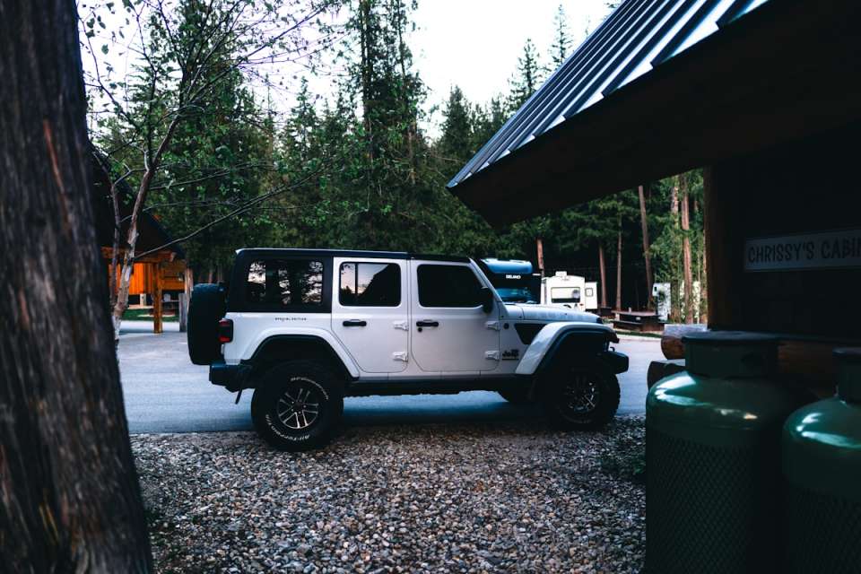 White jeep parked at a campsite near trees
