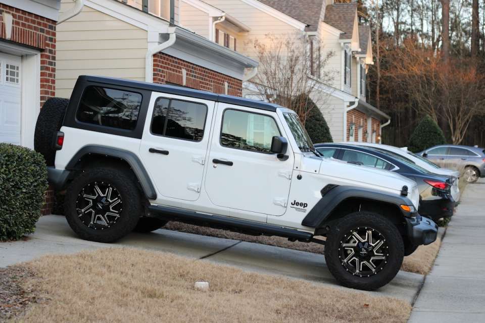 White jeep wrangler parked on a sloped driveway